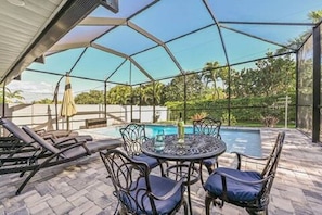 Screened in pool area w/chasers, umbrella, and table.