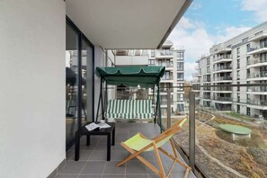 A private balcony with outdoor furniture and a view of a well-maintained residential area.
