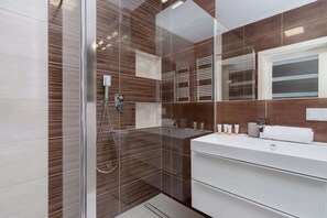 A stylish bathroom with a contemporary design, featuring brown tiles and a large mirror.
