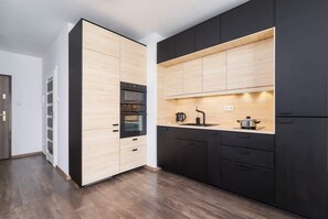 A sleek, modern kitchen with wooden and black cabinetry, featuring built-in appliances.
