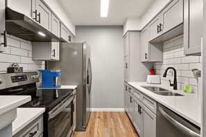 Fully stocked kitchen with quartz counters, stainless appliances, tile backsplash