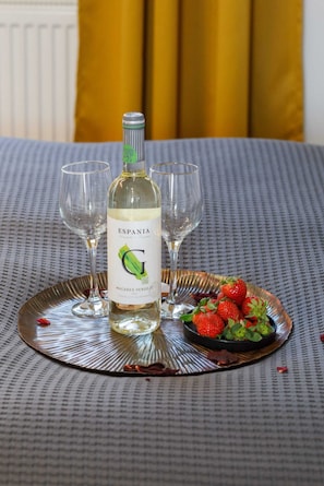 A close-up of a refreshment tray with a bottle of waine and fresh fruits for guests.
