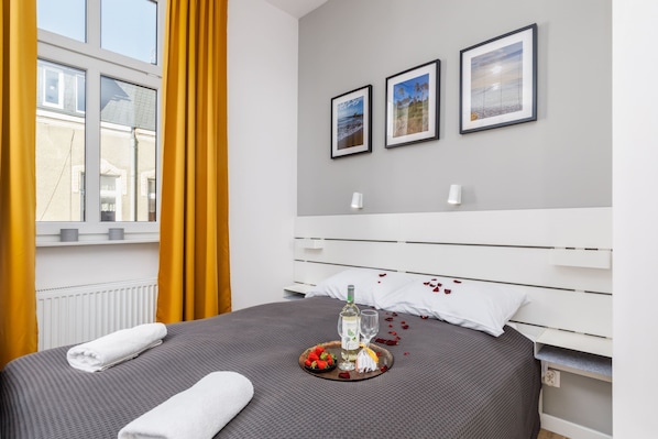 A bright bedroom with a comfortable bed, yellow curtains, and framed artwork.

