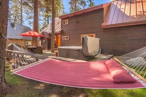 Beautiful landscaped backyard with knotty pine wood lounge chairs, a hammock, private hot tub and spacious deck with outdoor dining table and gas grill.