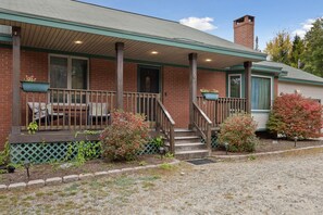 The front entrance includes a porch and a pair of rocking chairs.