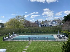 Large pool in backyard with plenty of seating and oversized umbrellas