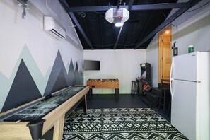 Garage game room includes shuffle board, arcade games, foosball, TV, &bar area. 