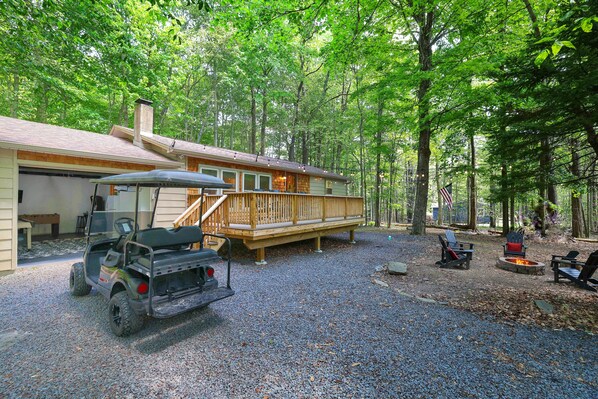 Large front yard with game room garage, golf cart available for rent, & fire pit