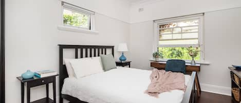 A calm, light-filled bedroom looking over a garden area.