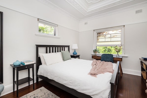 A calm, light-filled bedroom looking over a garden area.