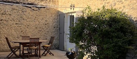 La maison et la terrasse ombragée à la pleine saison par une vigne