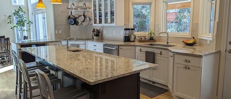 Kitchen with door on the right leading to the backyard. Island has 4 chairs.