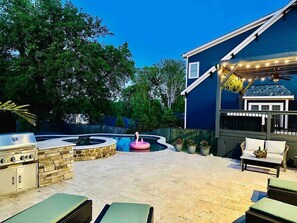 The backyard has a grill, sun loungers, and seating areas overlooking the pool and hot tub.
