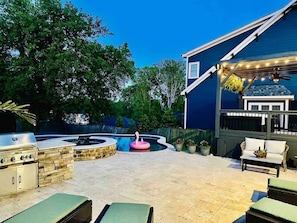 The backyard has a grill, sun loungers, and seating areas overlooking the pool and hot tub.