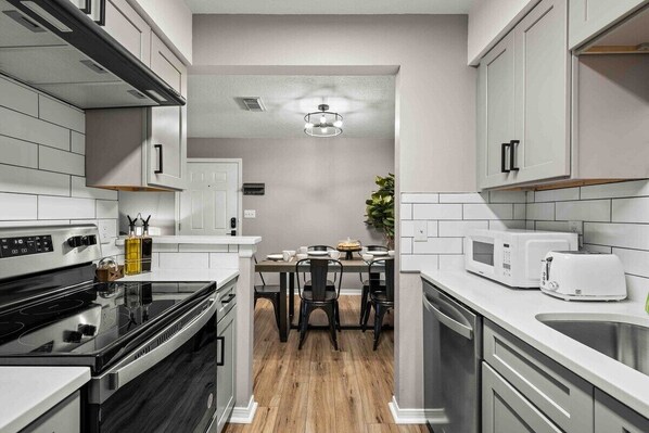 Kitchen view to dining room. All new cabinets and quartz counters. Stainless steel appliances, microwave, toaster, keurig coffee maker. 

