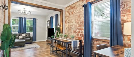 Dining are and office with exposed brick overlooking living room.