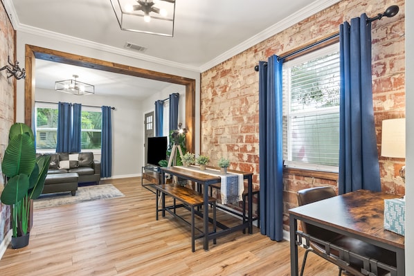 Dining are and office with exposed brick overlooking living room.