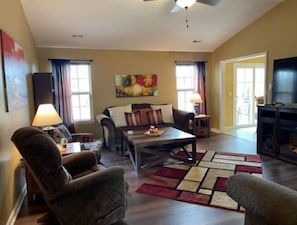 Spacious living room provides seating for seven, Roku TV, a selection of books.