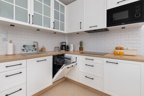 Modern kitchen with white cabinetry, a built-in microwave, and all the essentials for cooking.
