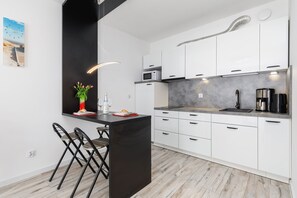 Contemporary kitchen with sleek white cabinets, a breakfast bar, and modern appliances for cooking convenience.
