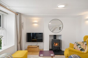 Copper Bal Cottage, Marazion. Ground floor: Living area with comfortable two seater sofa, armchair, wall-mounted Smart television and wood burning stove