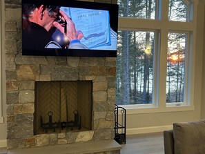 Living room fireplace has views of the lake and 65 inch smart tv