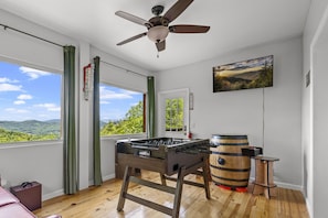 Cozy game room is a playful retreat equipped with a TV, a multi-cade game and a food ball game for family entertainment