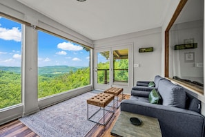 A sunroom with large picture windows framing natural beauty is the perfect spot for enjoying the first sip of morning coffee or melting into serene surroundings