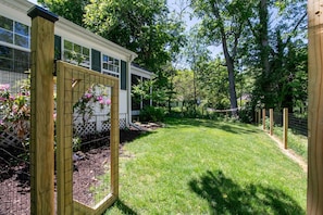 The lush fenced-in yard with serene rock fountain and double hammock
