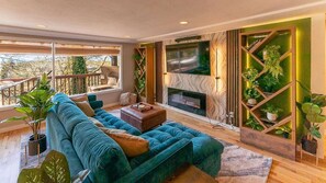 Main floor living room with large picture windows, 65" Smart TV and electric fireplace