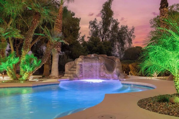 Sparkling pool with a cascading waterfall surrounded by lush greenery.