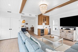 View of the living room with large smart TV, wet bar with drink fridge and ice maker