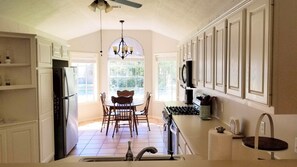 Functional kitchen furnished with dishes, pots/pans, coffee maker and more!