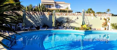 Community pool with sun loungers and outdoor shower