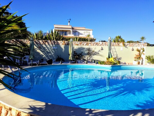 Community pool with sun loungers and outdoor shower