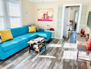 Living room has original art, TV with streaming services, and a sofa bed.