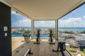 A modern rooftop fitness center with a view of the ocean - super motivational