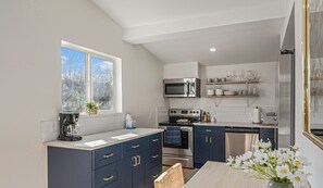 - Cook up your favorite meals in a sleek kitchen with navy cabinets and open shelving
- Natural light pours in while you prep, brew coffee, or grab a midnight snack
- Stainless steel appliances and thoughtful layout make cooking a breeze