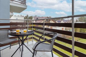 A spacious balcony with a seating area, overlooking a scenic outdoor view of the neighborhood and greenery.