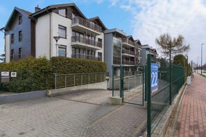 The front of a modern apartment complex with a gated entrance and a paved path leading inside.