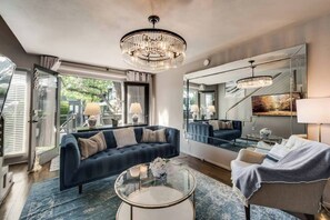 The spacious living room boasts an inviting open-concept design, with a massive Smart TV and comfortable sofa and chair, serving as the focal point for both relaxation and entertainment. French doors lead out to your private patio. 
