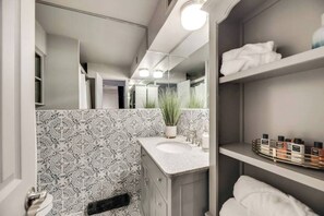 Spacious full bath featuring a relaxing tub and elegant marble countertops for a touch of luxury.