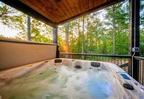 Enjoy a relaxing soak in the hot tub while the sun sets through the surrounding trees.