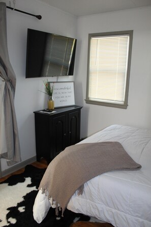 Bedroom has ample clothing storage with closet and dresser and features a smart TV