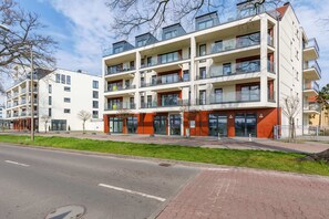 An exterior shot of a modern residential building with balconies and a landscaped pathway.