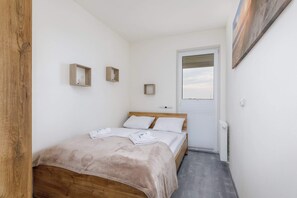 A cozy bedroom featuring a bed with a wooden headboard, white linens, and a side table for convenience.