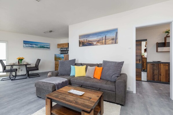 A bright living room with a gray sofa, colorful cushions, and a wooden coffee table, complemented by a modern decor style.
