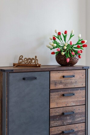A small wooden sideboard with drawers, topped with decorative plants and a "Beach" sign for charm.