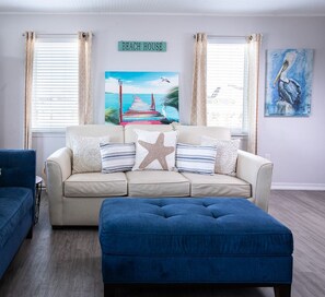 Relax in the spacious, naturally lit living room, where comfortable furnishings invite you to unwind after a day at the beach. It’s the perfect spot to gather, lounge, or simply enjoy the coastal light.