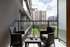 A balcony with a small table and two chairs, offering a nice outdoor seating area with a view of the surrounding apartment buildings. The space is perfect for relaxation.